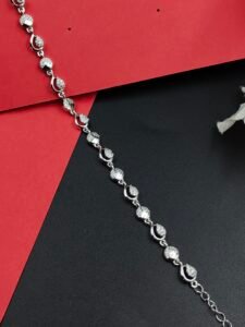 Celestial Orbit Silver Bracelet with alternating polished sphere motifs, textured spherical accents, curved orbit-inspired links, and an adjustable extension chain displayed on a contrasting red and black background.